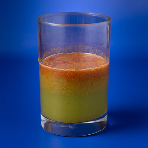 glass of juice with a green to orange gradient color
